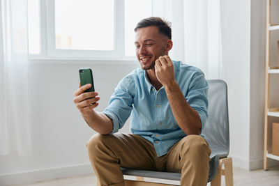 Young woman using mobile phone while sitting at home