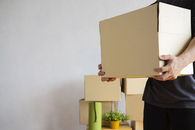 Midsection of person holding paper against wall