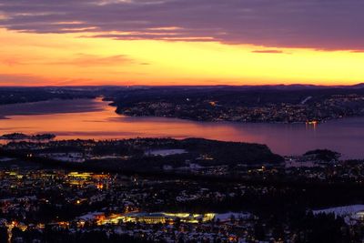 Aerial view of illuminated city against sky during sunset