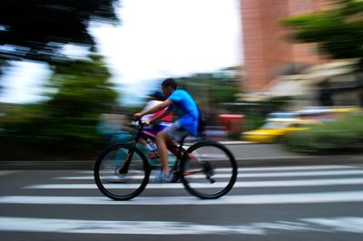 Blurred motion of people riding bicycle on road