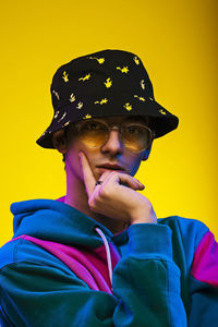 Portrait of boy wearing hat against yellow background