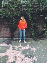 Full length of woman standing against brick wall