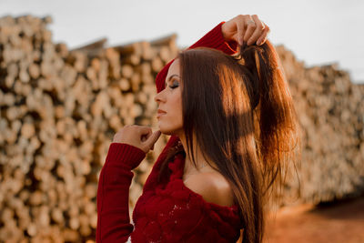 Side view of young woman with hand in hair standing outdoors