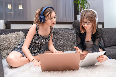 Friends using laptop while sitting on sofa at home