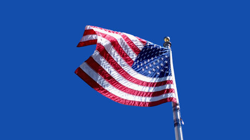 Low angle view of flags flag against clear blue sky