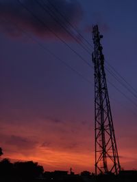 Low angle view of silhouette electricity pylon against sky at sunset