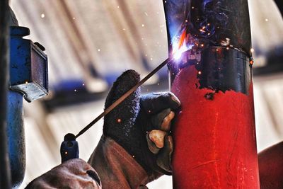 Close-up of manual worker welding metal in factory