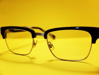 Close-up of eyeglasses on yellow background