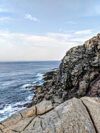 Rock formation on beach against sky