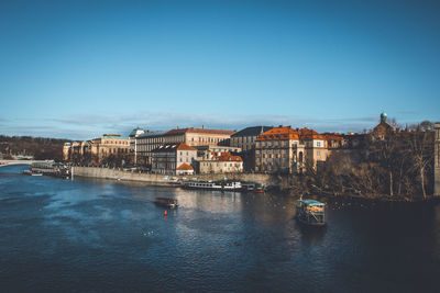 Scenic view of river by buildings against clear blue sky of old town in prague