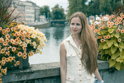 Portrait of young woman standing by flowers