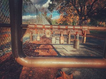 Empty park bench by trees against sky