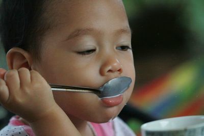 Close-up of girl drinking milk from spoon