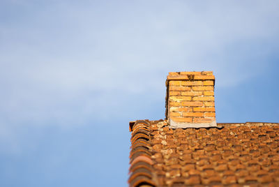 Low angle view of brick chimney on roof against sky