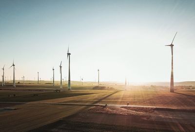 Wind turbines on field against clear sky