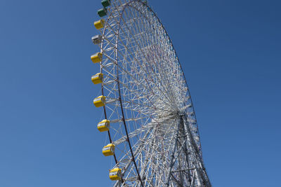 Low angle view of ferris wheel against clear blue sky