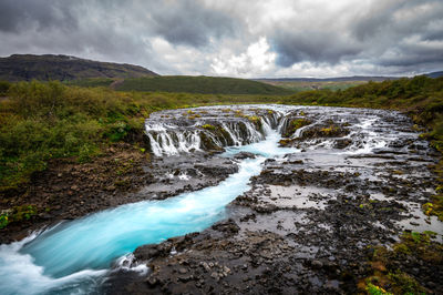 Scenic view of waterfall against sky