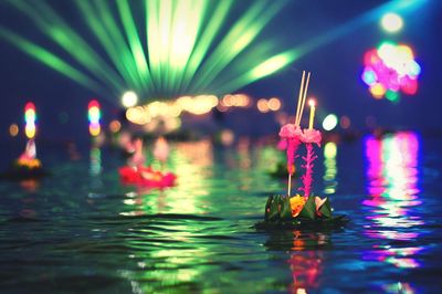 Religious offerings floating on water in river at night