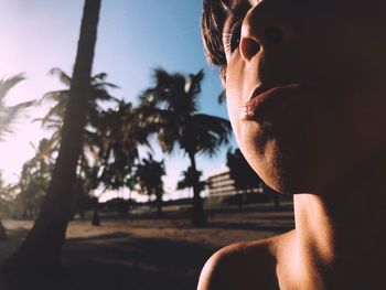 Close-up of shirtless boy making face against sky