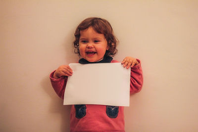 Portrait of a smiling young woman against wall