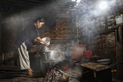 Side view of woman cooking in hut