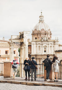 Rear view of tourist standing by railing against roman forum church