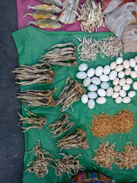 High angle view of dried fish and eggs on plastic at market for sale