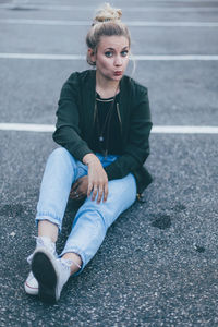 Full length of young woman sitting on road