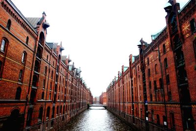 Canal amidst buildings against clear sky