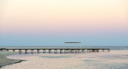 Pier over sea against sky during sunset