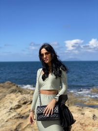 Young woman at beach against sky