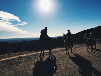 Silhouette of people horseback riding in countryside