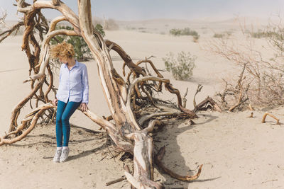 Woman sitting on dead tree