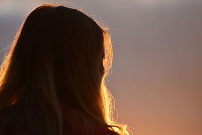 Rear view of woman against sky during sunset