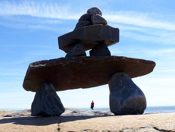 Rear view of man seen through stacked rocks by sea