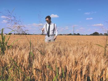 Well dressed man standing amidst plants against sky