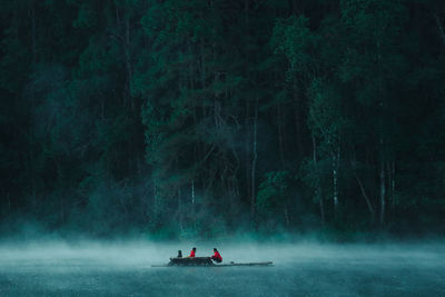 People in boat on lake in forest