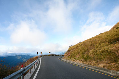 Empty road by mountain against sky