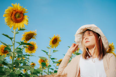 Young woman looking away on plants against sky