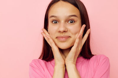 Portrait of young woman against pink background