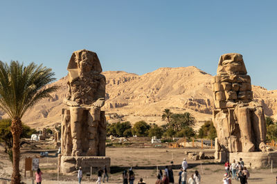 Front view of colossi of memnon statues in luxor, egypt with tourists sightseeing in a sunny day