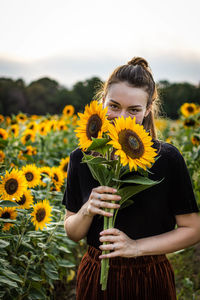Portrait of woman with sunflowers on field