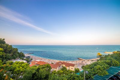 High angle view of townscape by sea against blue sky