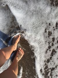 Low section of woman standing on shore at beach