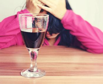 Woman sitting by wineglass at wooden table