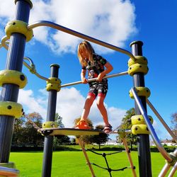 Low angle view of young child on climbing frame against sky