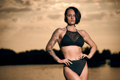 Portrait of beautiful woman standing against sky during sunset