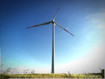 Low angle view of windmill on field against sky