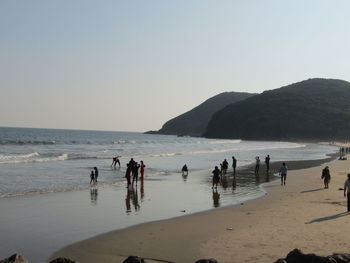 People on beach against clear sky