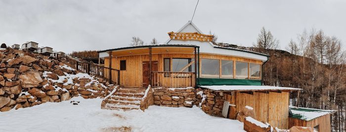 House on snow covered field against sky